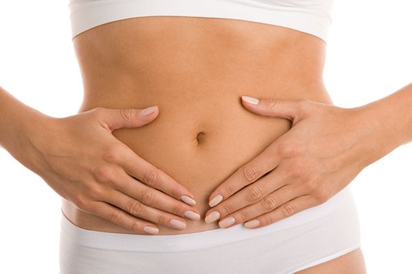 Woman experiencing soothing relief through BMT. Alt text: A person in white sportswear gently places both hands on their stomach, evoking the comfort found with Bioelectric Meridian Therapy. Description: Calm figure from chest to hips demonstrates serene ease after a BMT session; white background and manicured nails visible.
