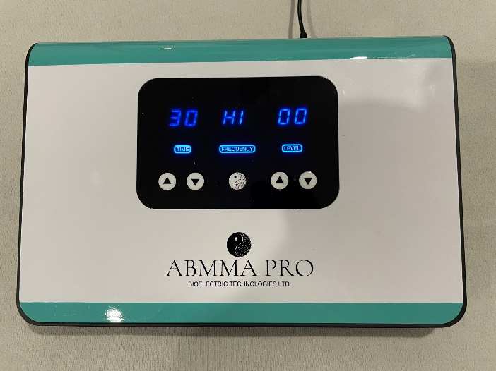 ABMMA PRO TENS Device for Bioelectric Meridian Therapy Description: BMT device with digital display, four controls, power indicator; white body with teal edges and black panel. Alt text: BMT equipment showing “30 HI 00” on screen, accented in teal and black, used for bioelectric meridian therapy.
